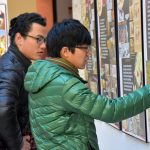 Dos estudiantes internacionales contemplan la muestra en el vestíbulo de Humanidades